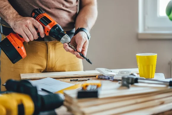 Person hält Akkuschrauber und Bohrer